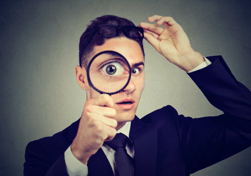Curious young man taking off glasses looking through a magnifying glass stock images Curious young man taking off glasses looking through a magnifying glass stock images