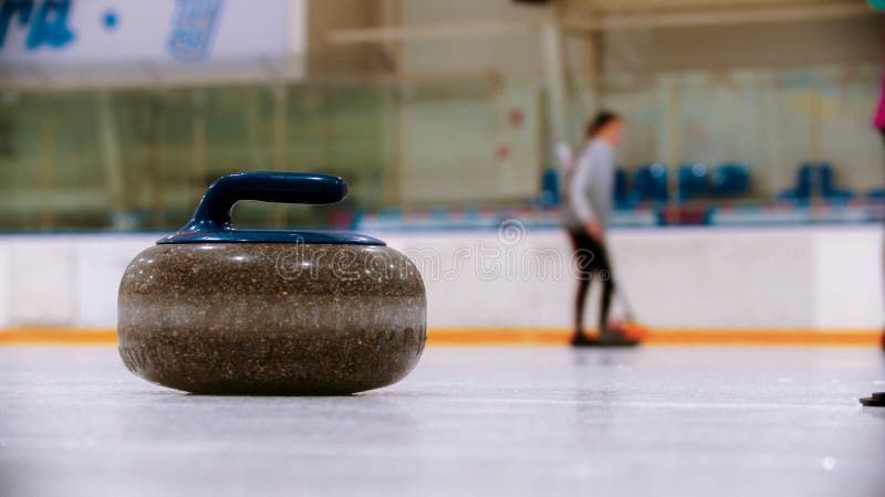 Curling - a granite stone with blue handle on the ice field royalty free stock image