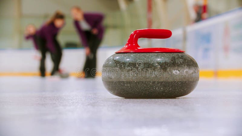 Curling - a granite stone with red handle on the ice field royalty free stock images
