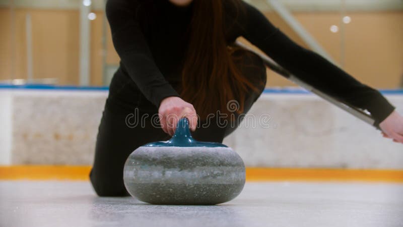 Curling - holding a granite stone with blue handle on the ice field royalty free stock photography
