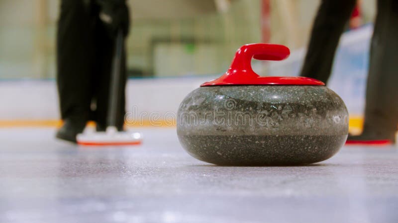 Curling training - a granite stone with red handle on the ice field royalty free stock photography