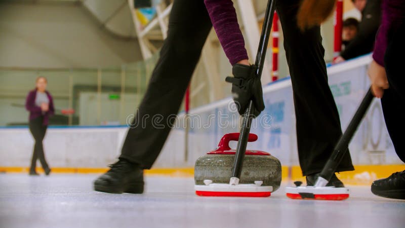Curling training - leading granite stone on the ice - clearing the ice before the stone stock photos