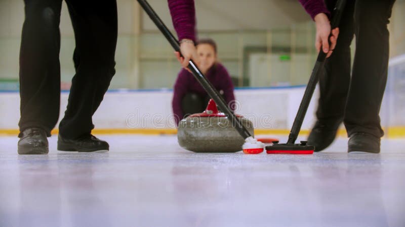 Curling training - leading granite stone on the ice and rubbing the ice before the stone - a woman watching the process royalty free stock images