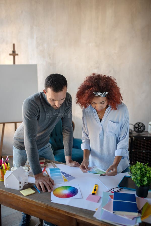 Curly assistant speaking with interior designer stock image