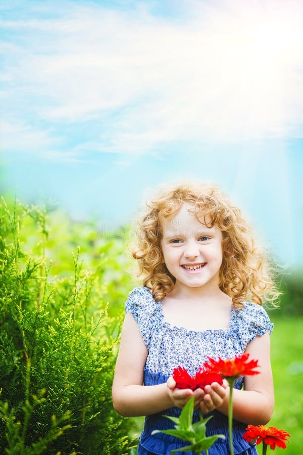 Curly baby with flowers in her hand.