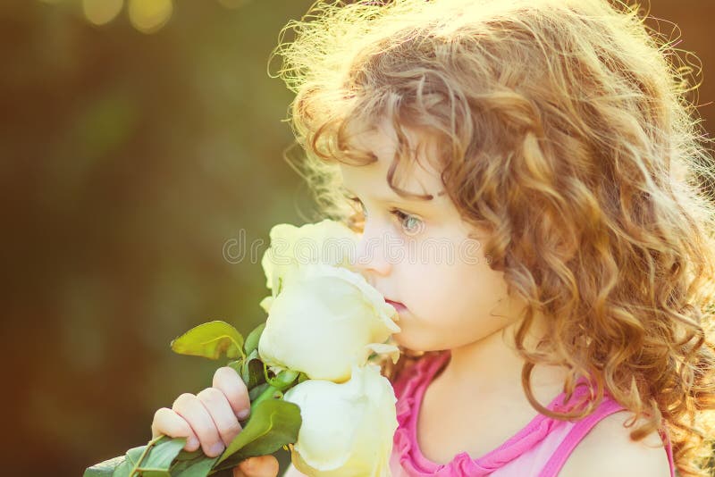 Curly baby with flowers in her hand. Toning photo. Instagram filter.