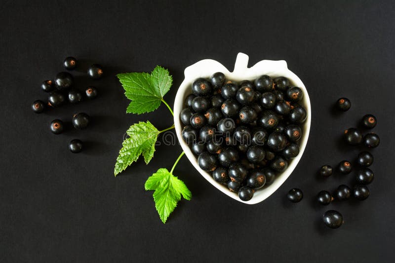 Currant berries in a white berry-shaped bowl on a black surface stock images