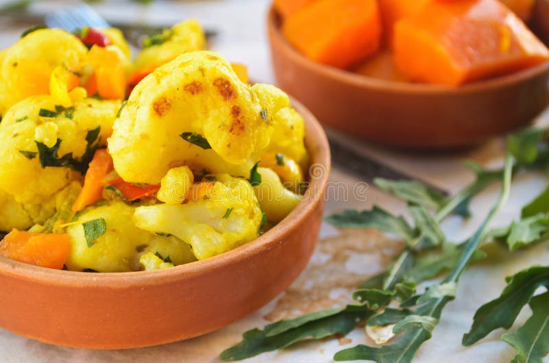 Curry de la coliflor con la calabaza, la paprika y el arugula foto de archivo libre de regalías Curry de la coliflor con la calabaza, la paprika y el arugula foto de archivo libre de regalías