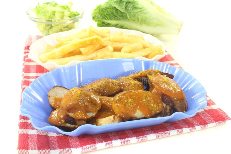 Currywurst med fransmansmåfiskar på en servett arkivbild