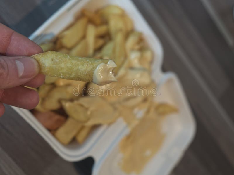 Currywurst med frites i en kopp. Den traditionella groddjursmaten som ska levereras med dip vid korona fokuserar på friska i hande royaltyfria foton