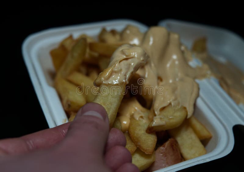 Currywurst med frites i en kopp på svart bakgrund. Traditionell groddjursmat att gå med dip vid korona och vara negativ arkivfoto