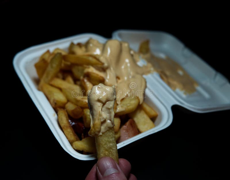 Currywurst med frites i en kopp på svart bakgrund. Traditionell groddjursmat att gå med dip vid korona och vara negativ arkivbilder