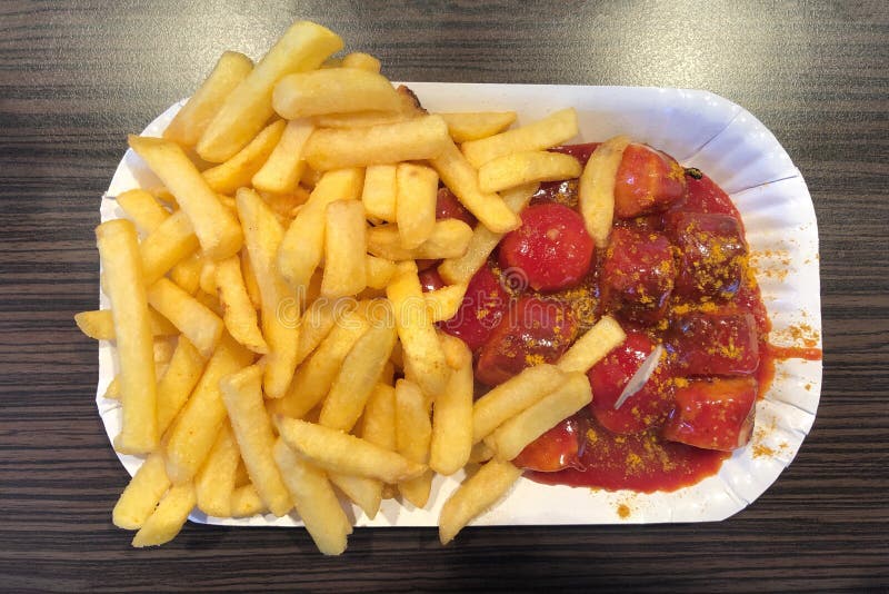 Currywurst tysk maträtt av den skivade korven med currysås och franska småfiskar arkivbild