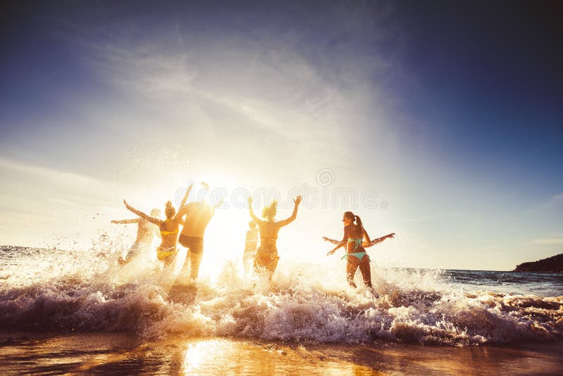 Big group of friends runs in sun light at the beach into the sea. Travel concept. Space for text. Big group of friends runs in sun light at the beach into the sea. Travel concept. Space for text