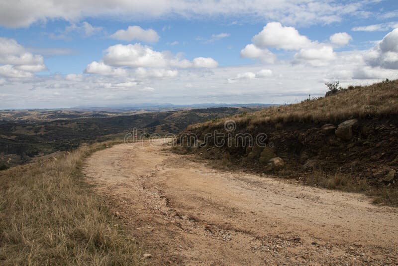 Curved Dirt Road on Hilltop Surrounded by Bleak Landscape stock photo