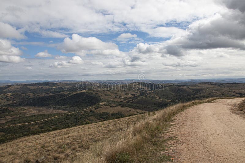 Curved Dirt Road on Hilltop Surrounded by Bleak Landscape stock photo