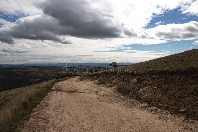 Curved Dirt Road on Hilltop Surrounded by Bleak Landscape stock images