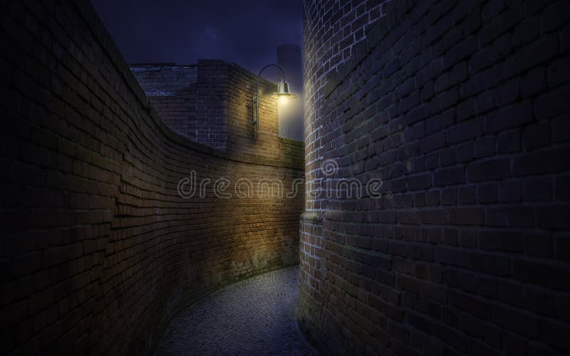 Curved pathway among old brick walls at night