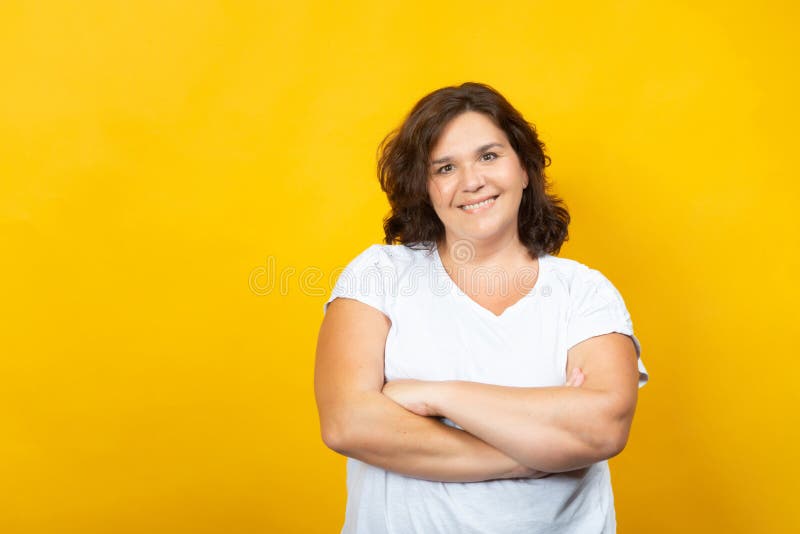 Curvy young woman smiling on a yellow background