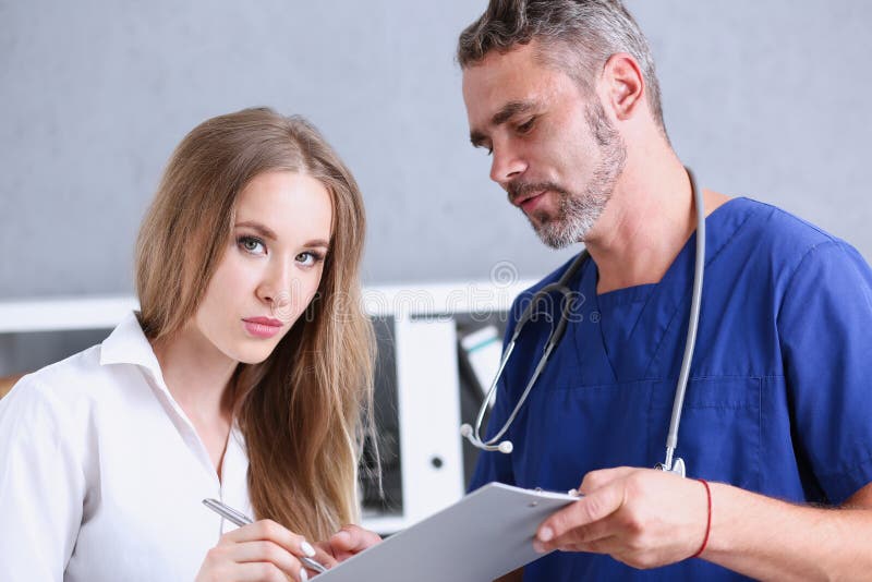 Cuscinetto maturo bello di offerta di medico da firmare con la penna d'argento immagini stock Cuscinetto maturo bello di offerta di medico da firmare con la penna d'argento immagini stock