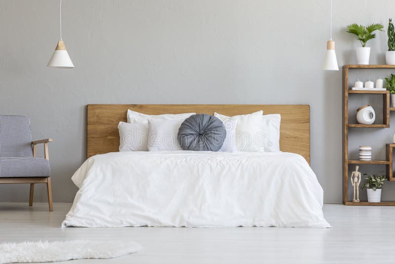 Cuscino blu sul letto bianco con la testata di legno in interi della camera da letto fotografia stock