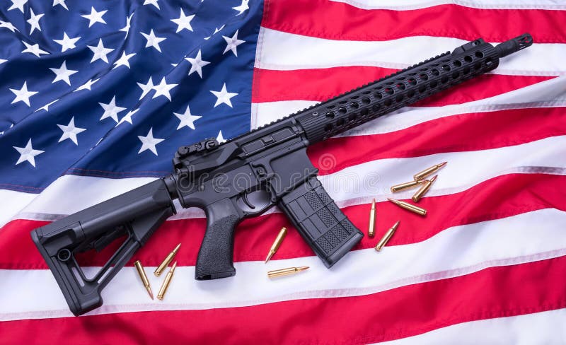 Custom built AR-15 carbine and bullets on American flag surface, background. Studio shot.