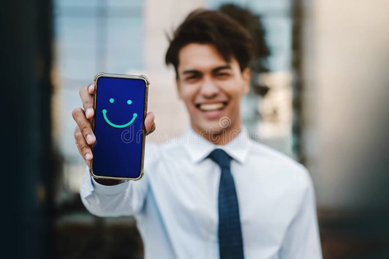 Customer Experiences Concept. Young Businessman Giving a Happy Face Icon and Positive Review via Smartphone. Client`s Satisfaction Surveys on Mobile Phone. Front View