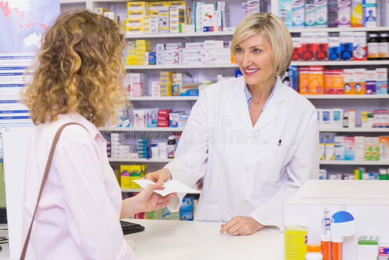 Customer handing a prescription to a smiling pharmacist royalty free stock image Customer handing a prescription to a smiling pharmacist royalty free stock image