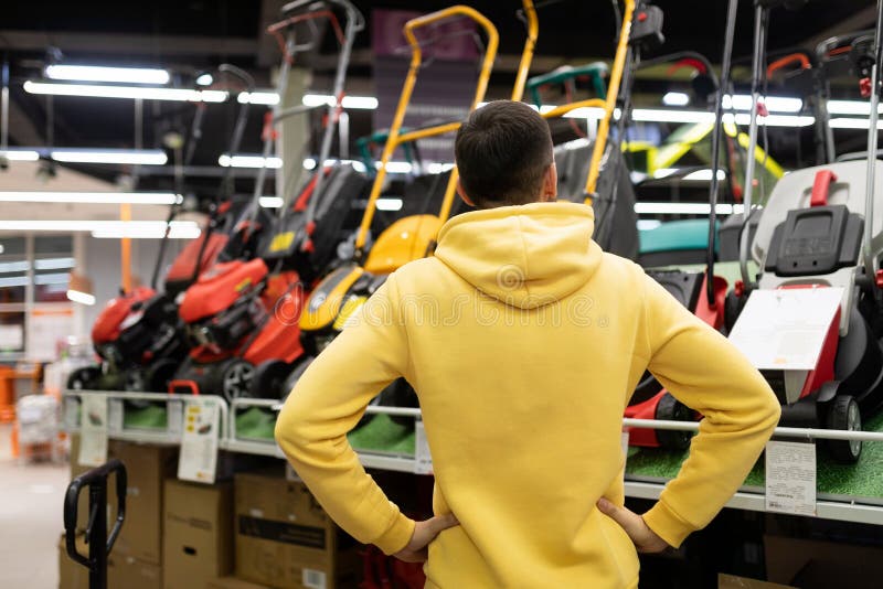 A Customer in a Hardware Store Chooses a Gas or Electric Lawn Mower