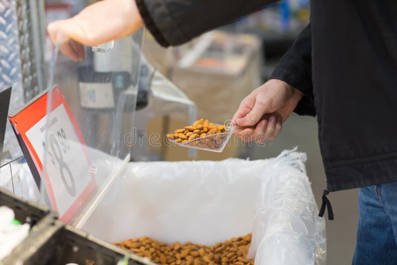 Customer Scooping Almond from the Bin in the Bulk Store Stock Photo
