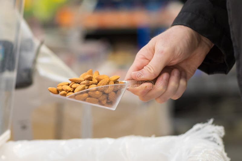 Customer Scooping Almond from the Bin in the Bulk Store Stock Photo