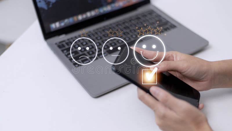 Customer service evaluation concept. using a smartphone is pressing face emoticon smiling in satisfaction on virtual touch screen royalty free stock image