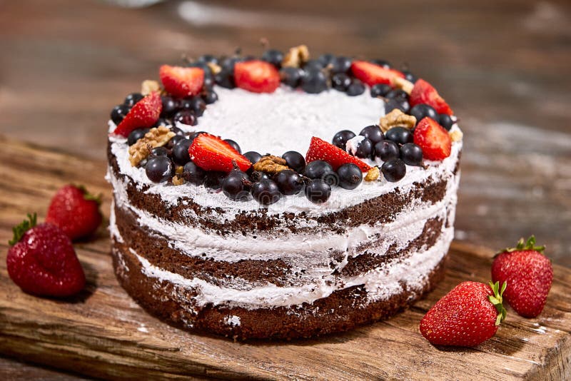 A cut of cake with whipped cream and strawberry fruits on wood table