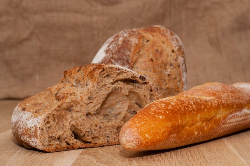 Cut into halves of black French bread and French loaf on the background of a wooden board and burlap