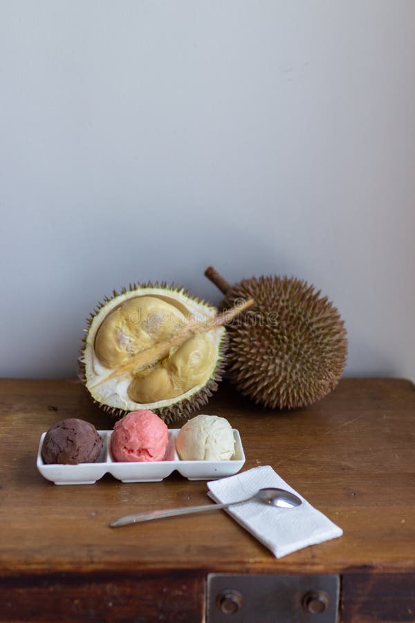 Cut open durian fruit on a wooden board with a triple scoop ice cream on a plate stock photo