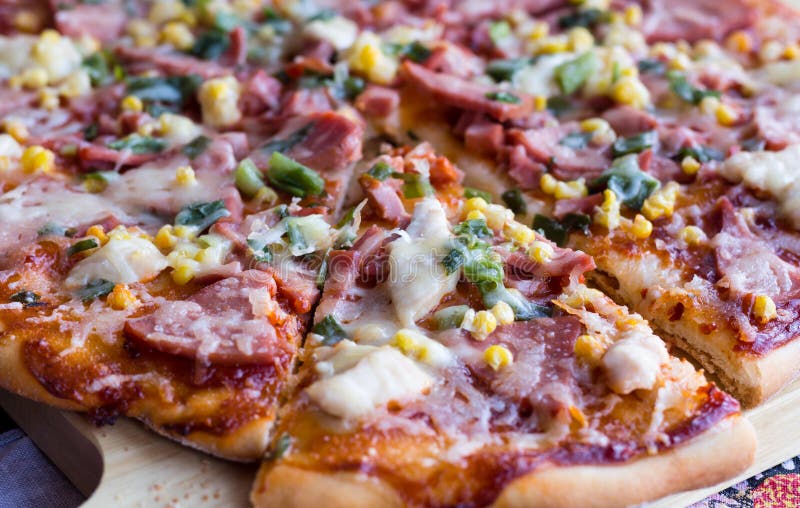 Cut on pieces pizza with sausage, chicken, corn and cheese