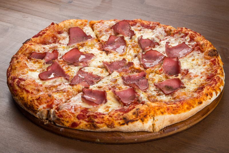 Cut into pieces of pizza with tomato, olives, sausage and cheese on a wooden platter