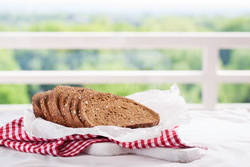 Cut in slices loaf of bread on a cut board on a kitchen background stock photos Cut in slices loaf of bread on a cut board on a kitchen background stock photos