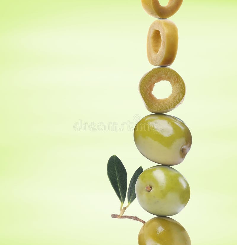 Cut and Whole Olives with Leaves on Yellowish Green Gradient Background