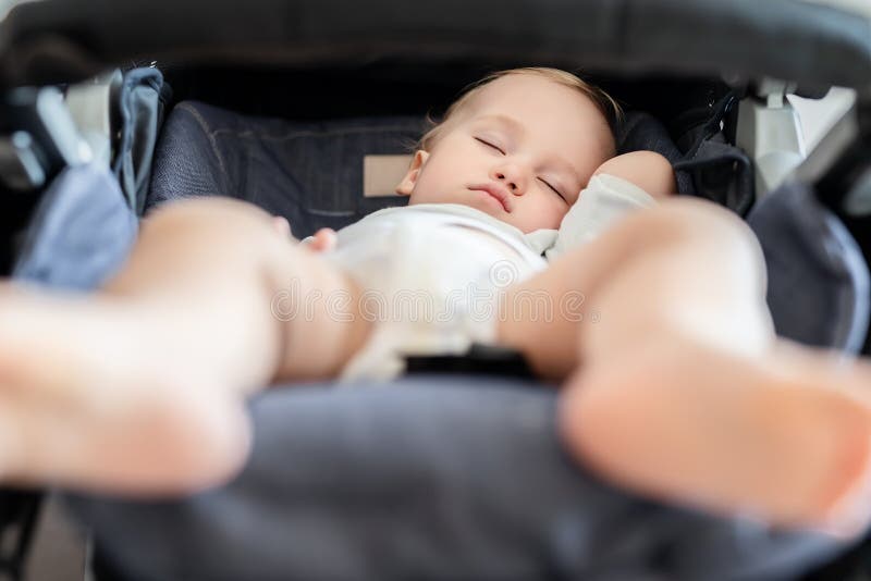 Cute adorable caucasian blond toddler bou sleeping in stroller at daytime. Children healthcare and happy childhood concept