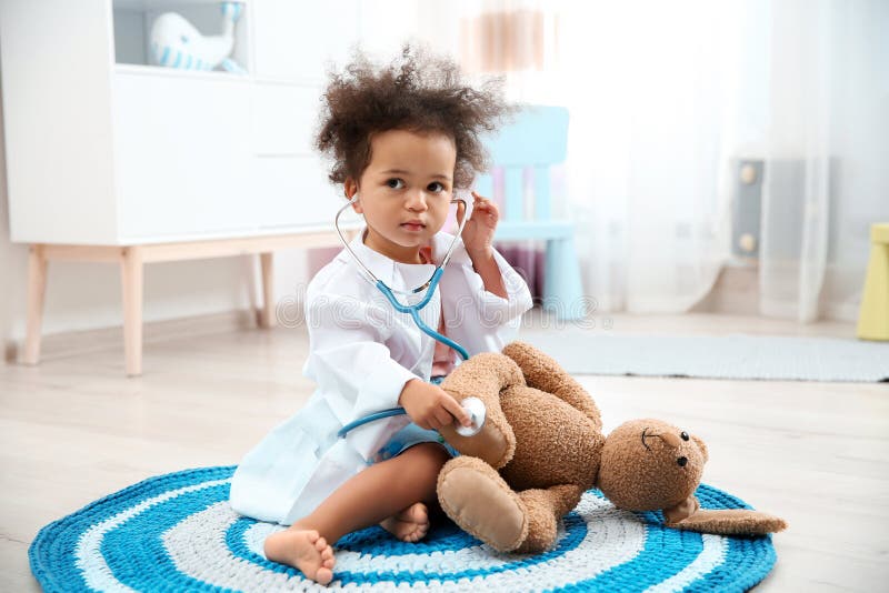 Cute African American child imagining herself as doctor while playing with stethoscope and toy bunny