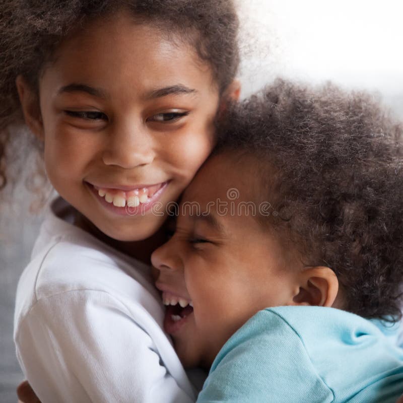 Cute african american kids with funny faces hugging laughing, 2 siblings boy and girl embracing having fun together, little brother and sister cuddling feeling connection, close up view, square crop. Cute african american kids with funny faces hugging laughing, 2 siblings boy and girl embracing having fun together, little brother and sister cuddling feeling connection, close up view, square crop