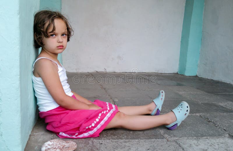 Cute Angry Girl is Sitting on the Floor, Looking at the Camera. Concept