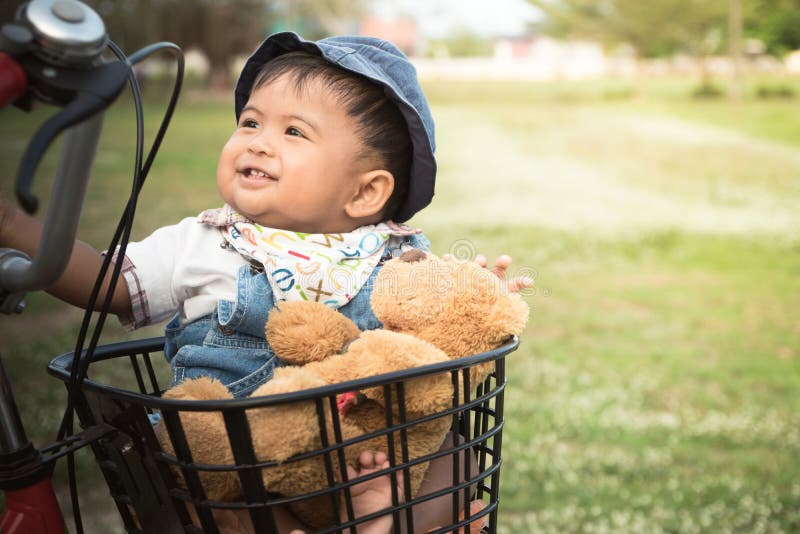 Cute asian baby sitting in bicycle basket,vintage tone