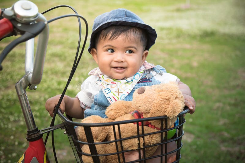 Cute asian baby sitting in bicycle basket,vintage tone