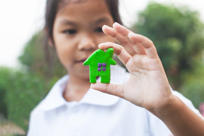 Asian child girl holding and playing plasticine clay house and heart with fun. Happy family and warm house concept