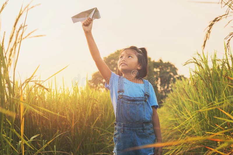 cute asian children playing paper airplane at rice field