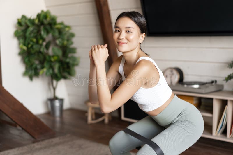 Cute Asian Fitness Girl at Home Doing Workout, Squats with Stretching ...