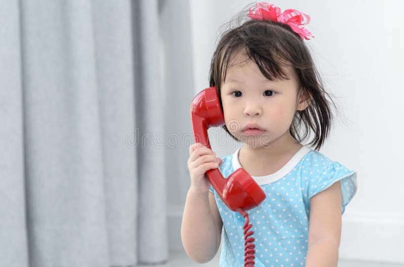Asian girl using red vintage phone at home.