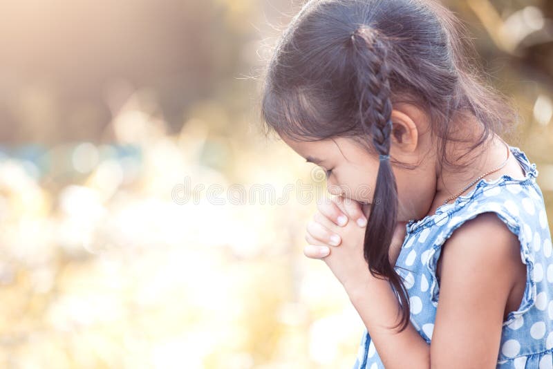 Cute asian little child girl praying with folded her hand for faith,spirituality and religion concept